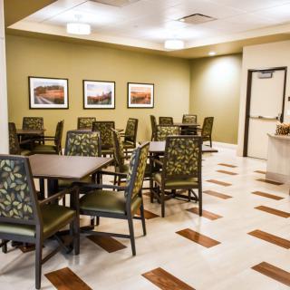 A clean and empty dining area with several tables and chairs, decorated with framed artwork on the walls.