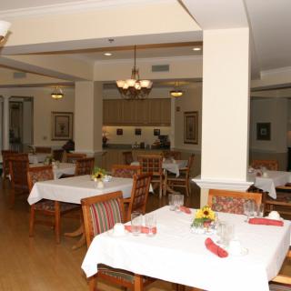 An empty dining room with neatly set tables and chairs, illuminated by warm indoor lighting.