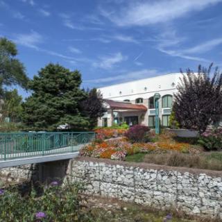A scenic view of a building with a garden and bridge in the foreground.