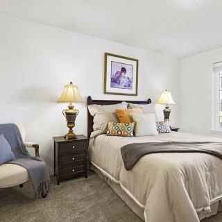 A cozy and well-decorated bedroom with a comfortable bed, bedside lamps, and artwork on the wall.