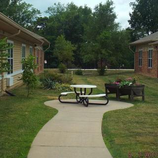 A peaceful garden path with a picnic table and benches between two buildings.