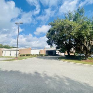 A view of a building surrounded by trees under a partly cloudy sky.