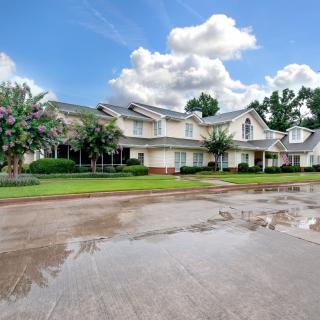 A picturesque residential house with a well-maintained front yard and a cloudy sky overhead.