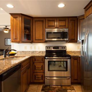A modern kitchen featuring stainless steel appliances, wood cabinets, and granite countertops.