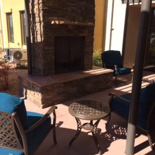 A cozy outdoor patio with comfortable seating around a stone fireplace.