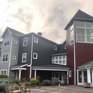 A modern multi-story residential building with a mix of dark and red exterior panels.