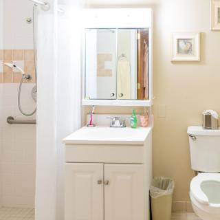 A small, clean bathroom with a shower, sink, and toilet.