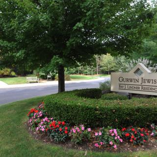 A well-maintained entry sign surrounded by vibrant flowers and greenery near a road.