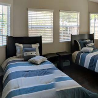 A cozy bedroom featuring two twin beds with striped bedding and ample natural light from the windows.