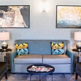 A cozy living room with a blue sofa, colorful pillows, and wall art.
