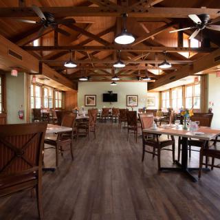 Spacious restaurant dining area with wooden furniture and natural lighting.