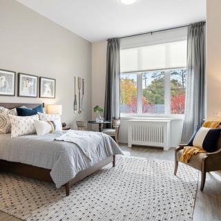 A modern and cozy bedroom with stylish decor, featuring a large window and comfortable furnishings.