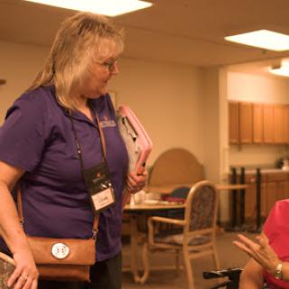 A caregiver engages in a warm conversation with an elderly woman at a community center.