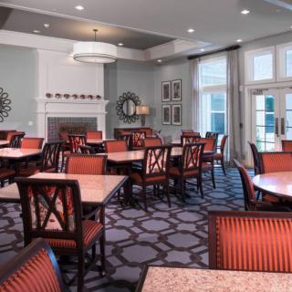 A well-decorated dining area with multiple tables and chairs, featuring a fireplace and large windows.