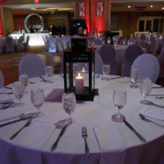 A beautifully set table at a wedding reception, featuring a central lantern with a glowing candle.