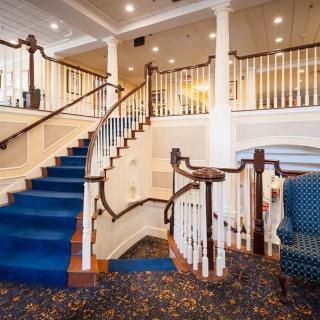 A grand staircase with a blue carpet in an elegant lobby setting.