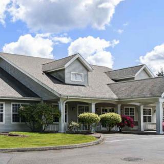 A charming residential house with a well-maintained front yard under a partly cloudy sky.