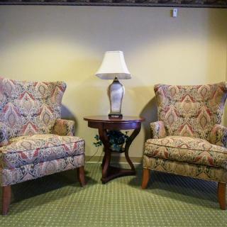 A cozy seating area with two patterned armchairs, a small wooden table, and a decorative lamp.