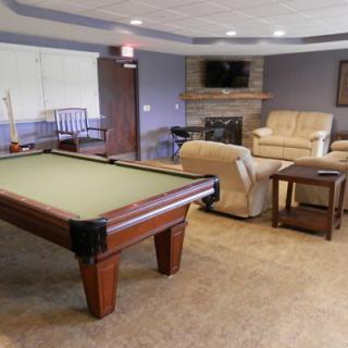 A cozy recreation room featuring a pool table, comfortable seating, and a television above a fireplace.