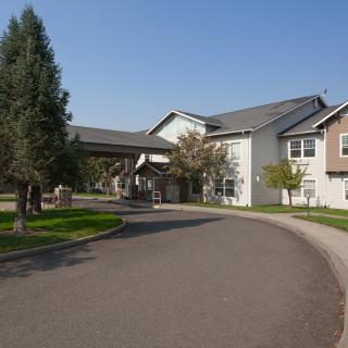 A residential building with a curved driveway and surrounding greenery.