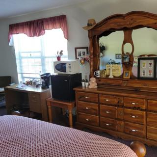 A cozy bedroom with a wooden dresser and a computer desk by the window.