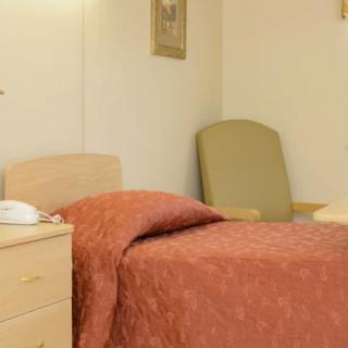 A simple hospital room with a bed, nightstand, and chair.