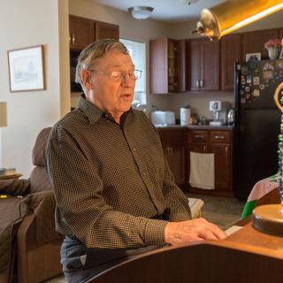 A man plays the piano in a cozy living room setting.