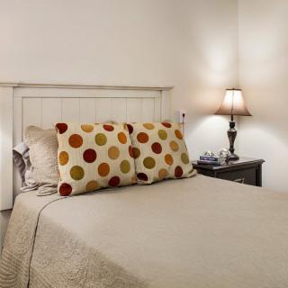 A cozy bedroom with decorative pillows and a bedside lamp.