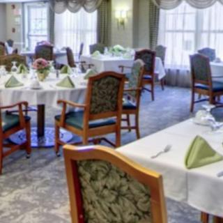 An elegant dining room with neatly arranged tables and chairs, featuring table settings and folded napkins.