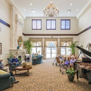 A spacious and elegantly decorated lobby with a chandelier, comfortable seating, and a piano.