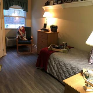 A cozy bedroom with a bed, chair, and warm lighting.