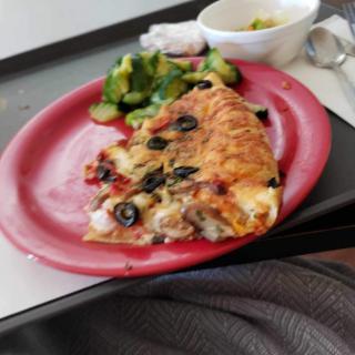 A tray with a slice of pizza and salad on a red plate.