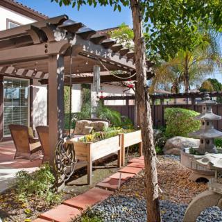 A serene backyard garden featuring a pergola and outdoor seating area.