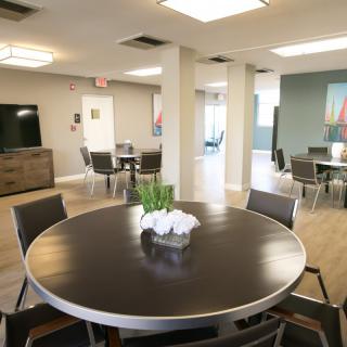 A modern meeting room with round tables and chairs, decorated with plants.
