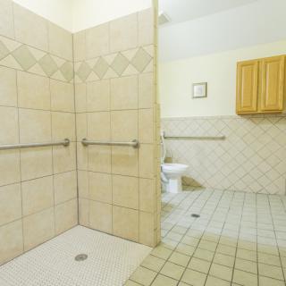 An accessible bathroom featuring a shower area with grab bars and tiled walls and floor.