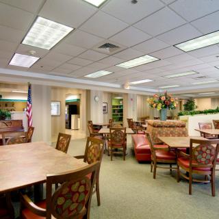 A spacious and well-lit lobby area with tables and chairs, an American flag, and decorative elements.