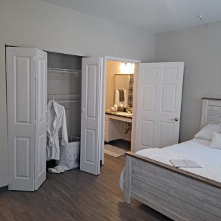 A cozy bedroom with an open closet and a view into the adjoining bathroom.