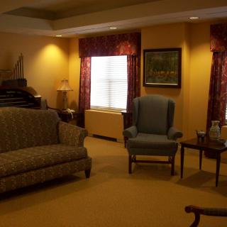 A cozy living room with a sofa, armchair, coffee tables, and decorative curtains.