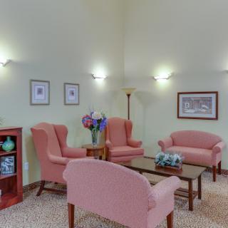 A cozy living room setup with soft pink chairs, a wooden coffee table, and decorative elements.