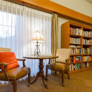 A cozy reading area with two chairs, a small table, and a well-stocked bookshelf.