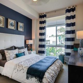 A modern bedroom with a stylish decor featuring striped curtains and wall artwork.