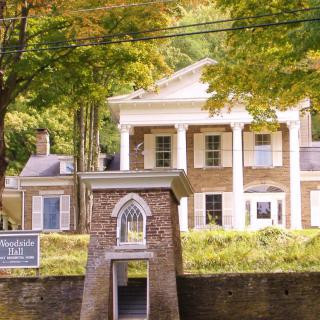An elegant historic mansion surrounded by lush greenery, showcasing classic architectural columns.