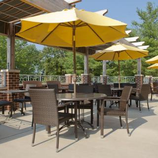 Outdoor patio with tables and yellow umbrellas on a sunny day.