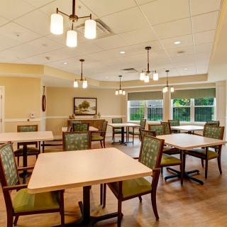 Spacious dining area with multiple tables and chairs, featuring elegant lighting and large windows.