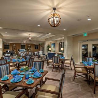 A spacious and elegantly designed restaurant interior with neatly arranged tables and blue napkins.
