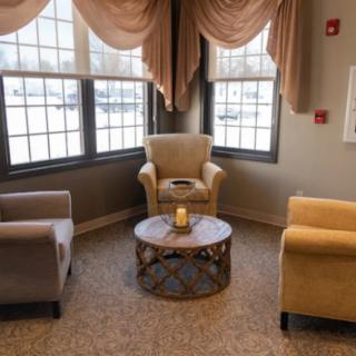 A cozy sitting area with three chairs and a small table by the window.