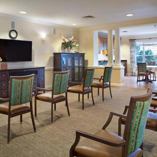 A well-arranged living room with a TV, cabinet, and multiple chairs.