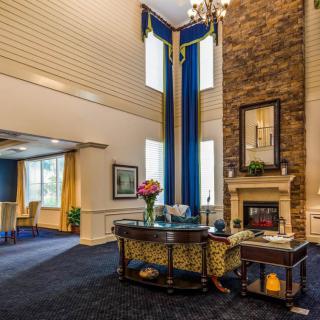 A stylish lobby with a fireplace and chandelier, featuring high ceilings and elegant decor.