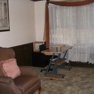 A cozy living room corner with an armchair and a small desk by the window.