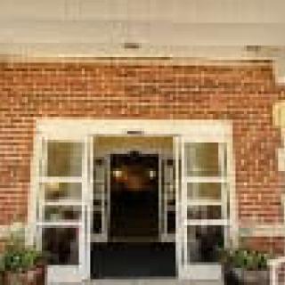 Entrance of a brick building with glass doors and potted plants.